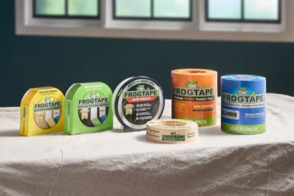 A selection of various rolls of painter's tape is displayed on a light-colored surface, with a backdrop of partially lit windows and a dark green wall, featured in the FrogTape $10,000 Sweepstakes