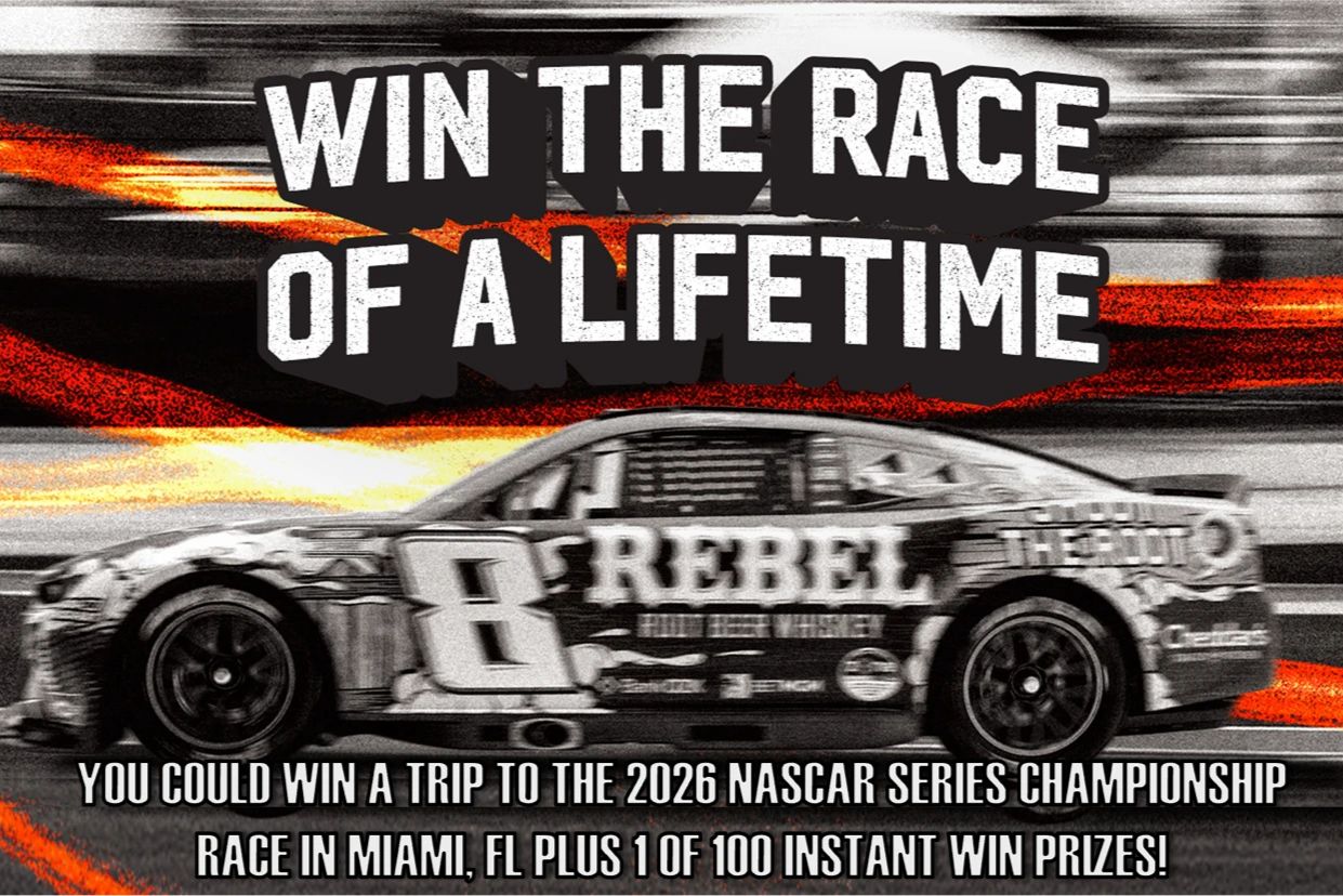 A high-speed NASCAR race car is captured in motion, showcasing its sleek design and vibrant colors against a blurred background, emphasizing the thrill of the competition, featured in the Rebel Bourbon Suite Sweepstakes