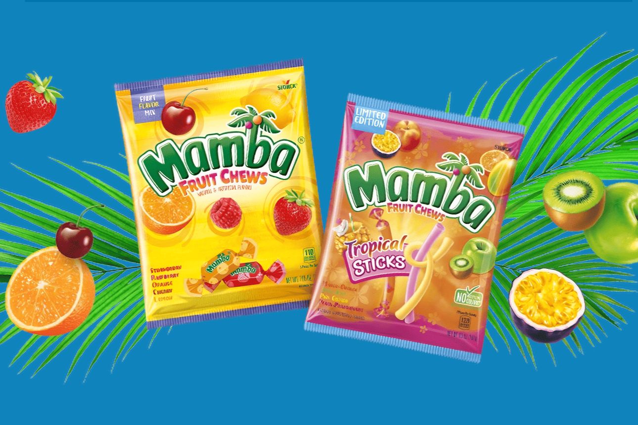 Two colorful packs of Mamba Fruit Chews are displayed against a vibrant blue background, surrounded by tropical fruits like oranges, cherries, and kiwis, featured in the Mamba Sweepstakes
