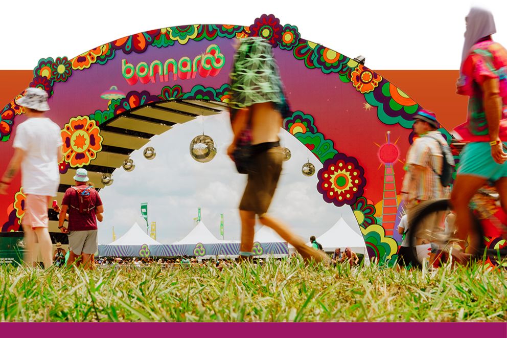 A colorful festival arch adorned with flowers welcomes attendees walking through, with vibrant tents visible in the background under a sunny sky, featured in the Five Below VIP Flyaway Sweepstakes