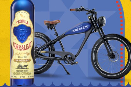 A stylish blue electric bike stands prominently against a vibrant background, while a bottle of tequila is placed alongside, creating a lively and festive atmosphere, featured in the Corralejo Tequila Bike Sweepstakes