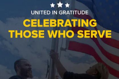 Two individuals are raising an American flag against a backdrop of clouds and blue sky, embodying a moment of patriotism and gratitude, featured in the Hertz Home Depot Car Sweepstakes