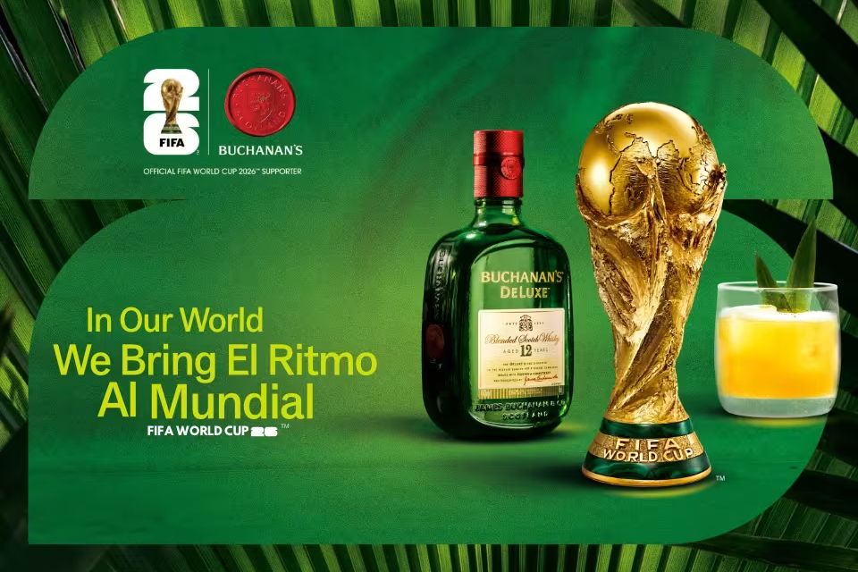 A sleek bottle of Buchanan's whiskey stands beside a golden FIFA World Cup trophy, accented by a refreshing cocktail garnished with mint, all set against a vibrant green background, featured in the Buchanan's World Cup Tickets Sweepstakes