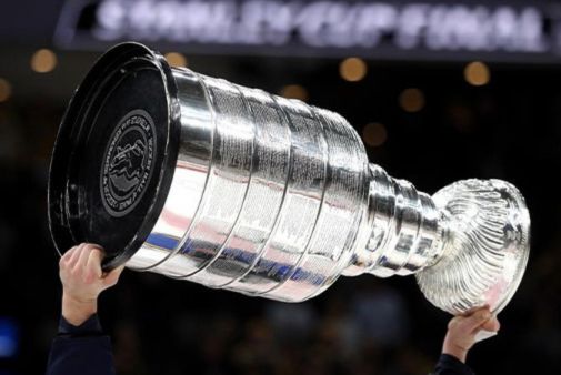 A person raises the iconic Stanley Cup high above their head, celebrating a significant achievement in hockey amidst a lively crowd in the background, featured in the Sony Stanley Cup Final Sweepstakes