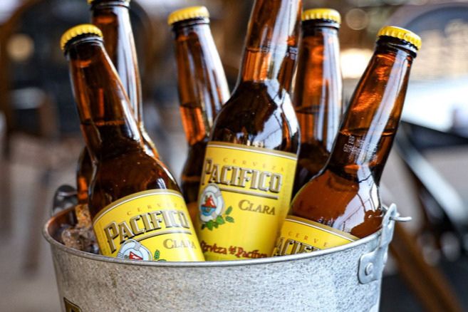 A metal bucket filled with ice holds several bottles of Pacifico Clara, showcasing their golden labels and reflecting light in a casual setting, featured in the Pacifico Personal Watercraft Sweepstakes