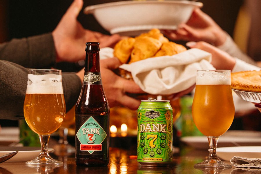 A festive gathering features hands reaching for a basket of golden pastries, while two glasses of beer sit on the table, creating a warm, communal atmosphere, featured in the Boulevard Gift Card Sweepstakes