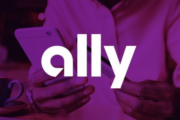A person holds a smartphone in one hand and a credit card in the other, with a coffee cup in the background, set against a colorful, blurred backdrop, featured in the Ally Make It Rain Sweepstakes