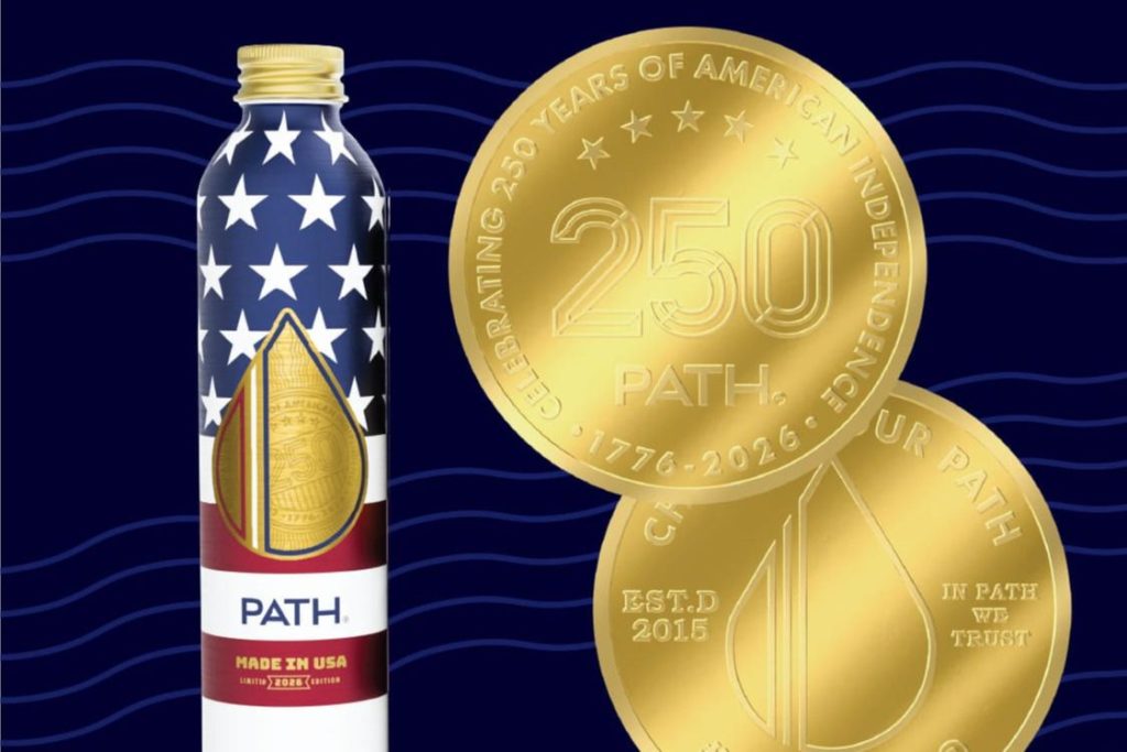 A decorated beverage bottle featuring a stars-and-stripes design stands beside two gold commemorative coins, highlighting an American independence celebration theme with the number 250, featured in the Made In the USA Sweepstakes 2026