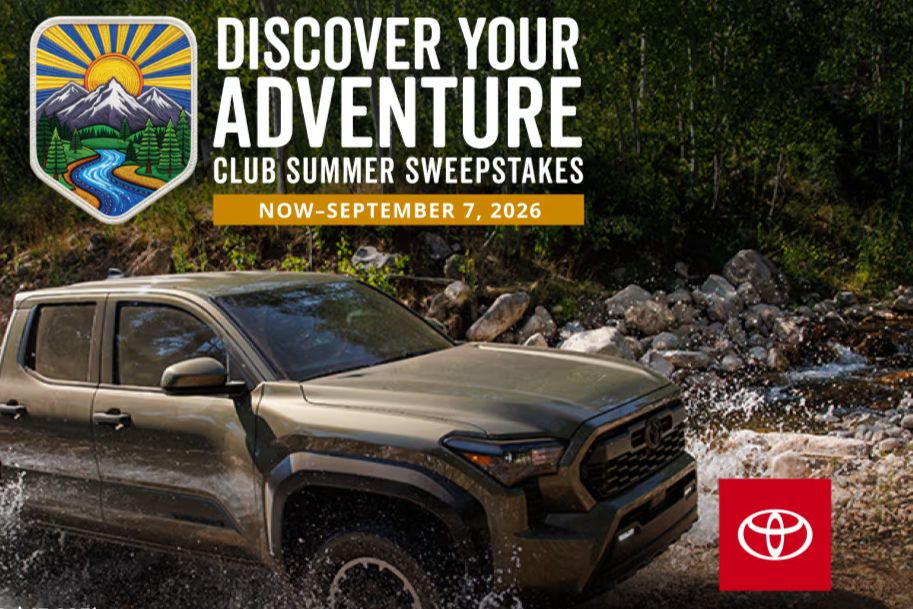 A rugged vehicle splashes through a stream surrounded by lush greenery, highlighting an adventurous outdoor scene. The backdrop features mountains and trees, emphasizing the spirit of exploration, featured in the Bass Pro Cabela's Adventure Sweepstakes