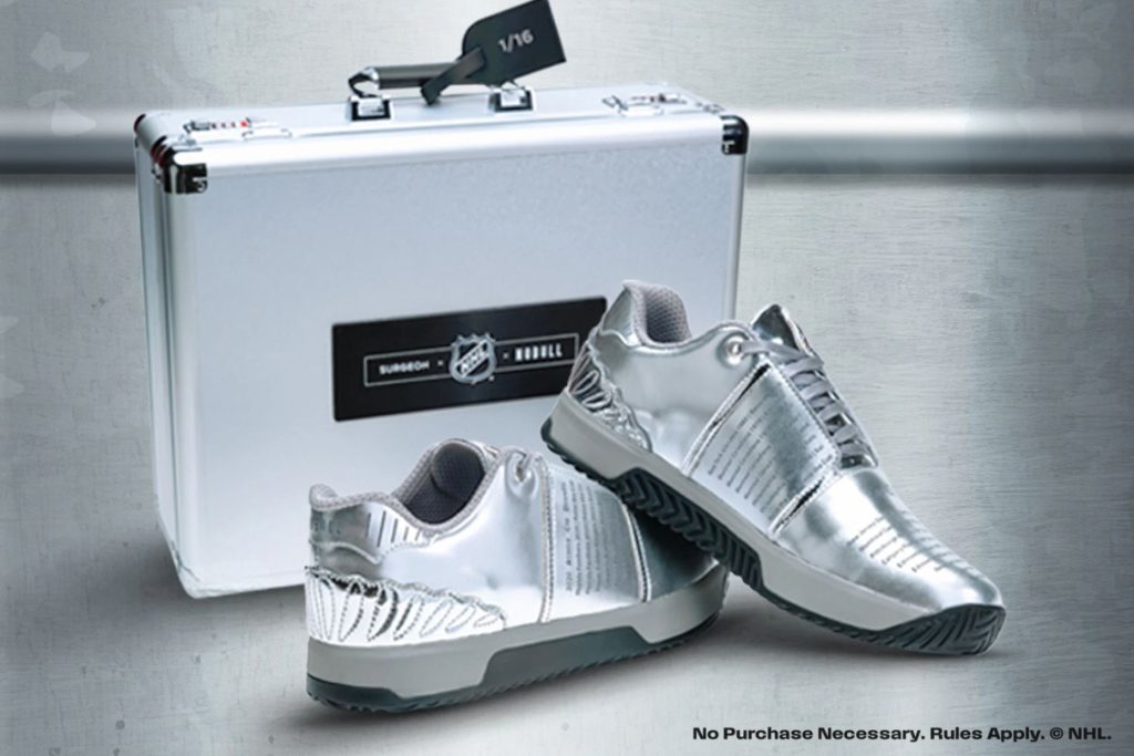 A pair of shiny silver athletic shoes rests on a surface next to a sleek silver case, highlighting their modern design and appeal, featured in the NHL Custom Shoes Sweepstakes