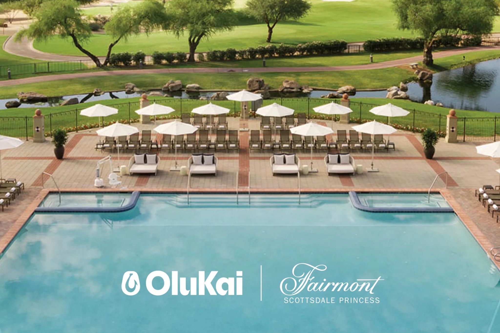 A serene pool area features sun loungers and umbrellas, surrounded by lush greenery and a pond, creating a relaxing outdoor getaway, featured in the OluKai Fairway Trip Sweepstakes