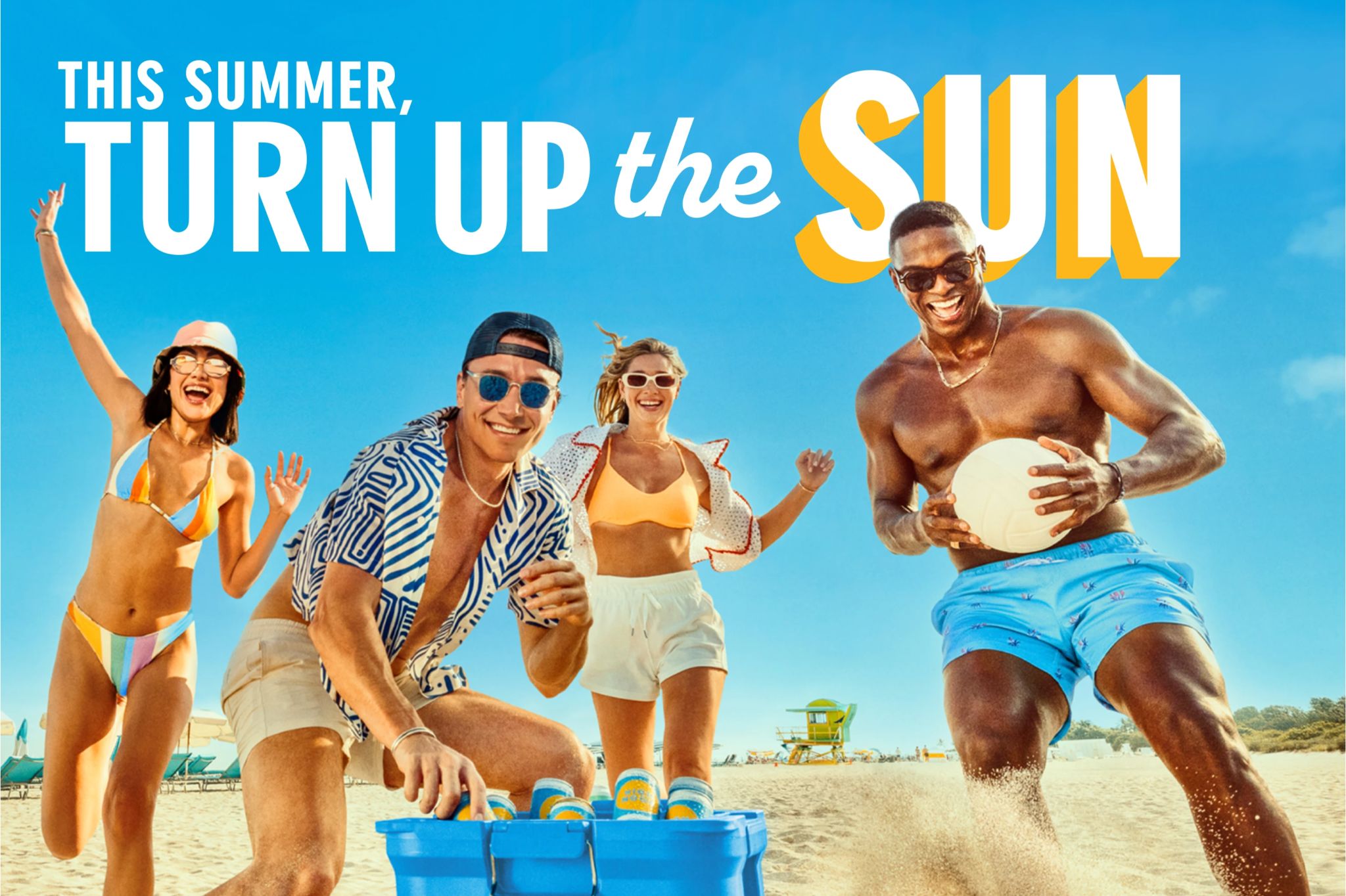 A group of four friends enjoys a sunny day at the beach, laughing and running towards the camera, with one man holding a ball while another crouches by a blue cooler, featured in the High Noon Travel Sweepstakes
