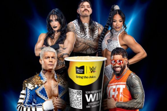 A group of five wrestlers poses together, showcasing their outfits and expressions, with a large cup in front. The backdrop is vibrant and dramatic, enhancing the lively scene, featured in the Coca-Cola WWE SummerSlam Sweepstakes